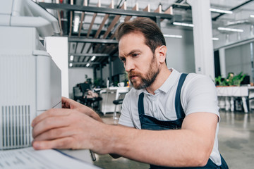 Wall Mural - close up view of male handyman repairing copy machine in modern office