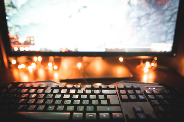 Background. Keyboard, mouse and computer monitor at night with warm lighting. Workplace at the computer at night. Copyspace. Gaming background