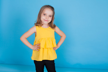 Portrait of a little girl in a yellow dress on a blue background