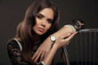 © Victoria Andreas - Elegant lady with Watch on hand. Beautiful woman with long healthy wavy hair style posing in studio on dark background.