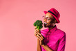 © Carlos David - Eat your vegetables, Portrait of a young woman biting into a raw broccoli, isolated in pink studio background