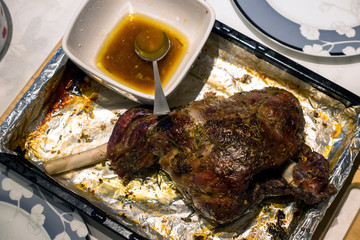 A roast leg of lamb on baking tray on christmas table