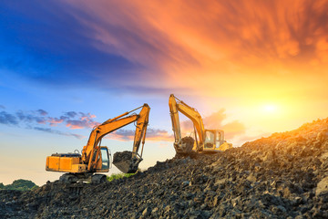 Wall Mural - Two excavators work on construction site at sunset