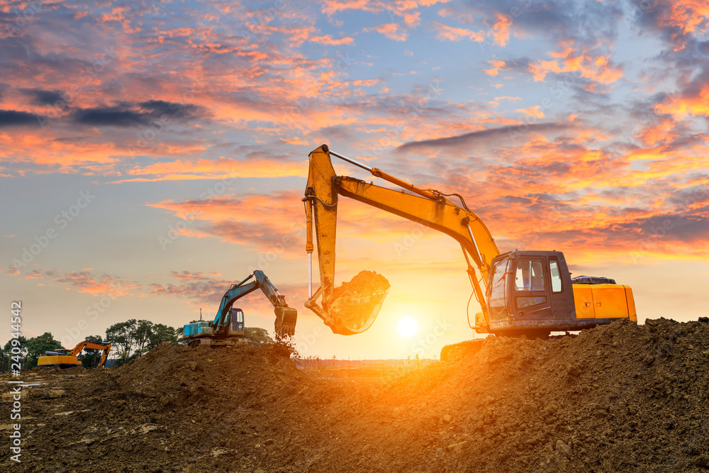 Three excavators work on construction site at sunset - obrazy, fototapety, plakaty 