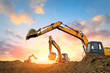 Three excavators work on construction site at sunset
