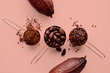 Rose gold measuring cups of cocoa beans, cacao nips, cocoa powder and cocoa pods on a pink background, flat lay healthy food concept