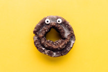 Funny Shock Face Glazed Chocolate Cake Donut On A Pastel Yellow Background, Creative Minimal Halloween Concept