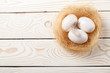 © yana_kallas - Easter background. Easter white eggs and feather in nest on rustic white wooden background. Top view, copy space