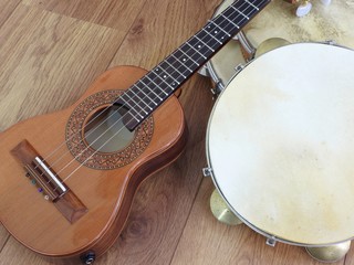 Close-up of two Brazilian musical instruments: cavaquinho and pandeiro (tambourine) on a wooden surface. They are widely used to accompany samba and choro, two popular Brazilian rhythms.