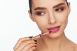© Andriy Goncharenko - Portrait of a beautiful young woman putting lipstick on her lips