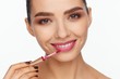 © Andriy Goncharenko - Portrait of a beautiful young woman putting lipstick on her lips