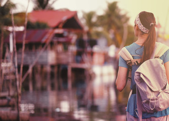 Back side of Young traveling women with backpack in fisherman village are walking in evening at asian, town. Happy female traveler and tourist concept.