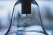 Glas Lampen Schirm einer Hänge Leuchte. Die Deckenlampe mit Glühbirne befindet sich vor einem Bokeh aus grau blauem Hintergrund