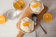 Creamy rice pudding with orange slices in bowls served on wooden table, top view