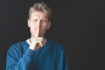 Wall Mural - handsome male holding his finger on lips in total silent