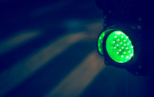 Green Traffic Light With Pedestrian In Background In Rainy Night