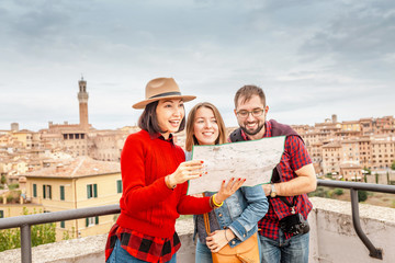 multiracial group of friends tourists looking at map in an old city in italy. travel and adventure c