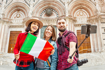 Wall Mural - Travel with friends in Italy. Multiethnic diverse group of young people taking selfie in front of a famous landmark the Duomo cathedral in Siena, Tuscany