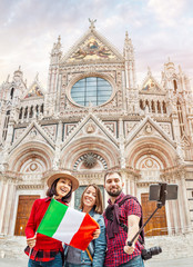 Wall Mural - Travel with friends in Italy. Multiethnic diverse group of young people taking selfie in front of a famous landmark the Duomo cathedral in Siena, Tuscany