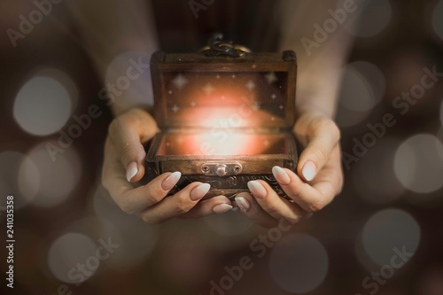 Fotografía opened wooden magic box on hands, lights from little chest, dreams in hands, bel