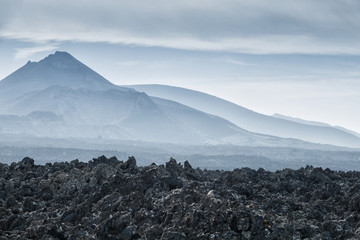 volcanic landscape with black lava field and volcano