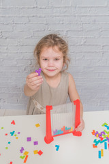 child, girl in a dress playing logic designer, on a white wall background