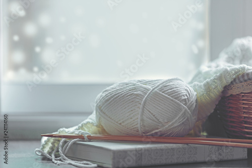 Fotografie, Obraz Cozy winter home with warm knitted sweaters and ball of yarn near windowsill, home hobbies, vintage tone