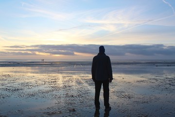 Mann betrachtet den Sonnenuntergang am Wattenmeer, Nordseeinsel Fanö, Dänemark