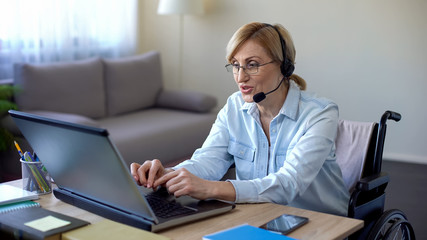 Senior disabled woman in headset applying for job from home, video conference