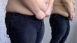 © motortion - Obese man trying to button up jeans, overweight problem, unhealthy lifestyle