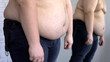 © motortion - Frustrated obese man looking at fat belly mirror reflection, weight loss problem
