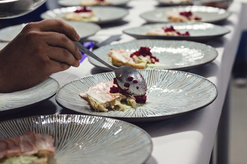 Closeup of chef preparing tasty gourmet dishes with delicious ham appetizer serving with beet on top garnishing