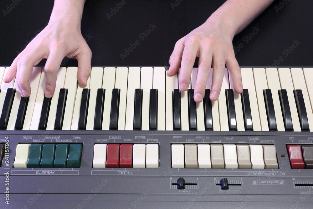 A right hand playing a B (SI) major chord on an old black piano with yellowed cracked keys, pressing the B (SI), D# sharp (RE#), F# sharp (FA#) notes - obrazy, fototapety, plakaty 