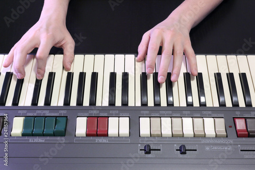 Fotografija A right hand playing a B (SI) major chord on an old black piano with yellowed cr