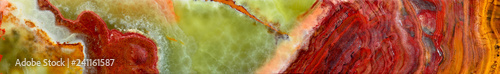 Fototapeta Onyx is a variety of agate. The texture of the surface of a beautiful stone. Green, brown, red, white, yellow color of the stains on a semi-precious mineral. Panoramic view