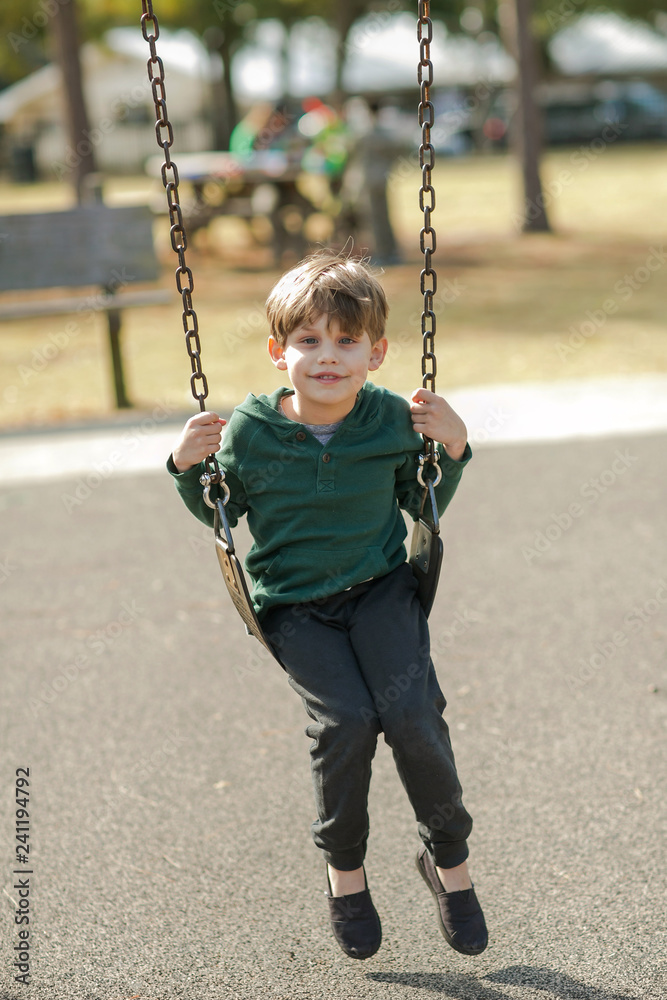 Little Boy Swinging on Swing at Park Playground Stock Photo