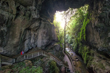 Boardwalk That Passes Through A Limestone Gorge & Under A Natural Stone Arch With Stalactites. Young Traveler Girl Explores Majestic Cave In North Island, New Zealand.