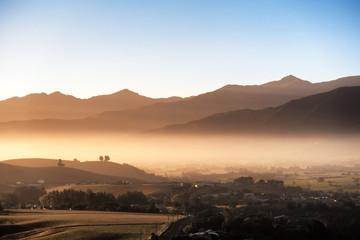 A brand new day arrives. As the sun shines through the low layer clouds, a heavenly golden light ray forms across the land. The atmosphere looks breathtaking. This image is suitable for travel use.