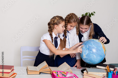 Fotografía three girls schoolgirls on the lesson of geography with a globe in school