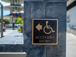 Gold and black accessible entry sign posting with wheelchair handicap logo with arrow pointing to left