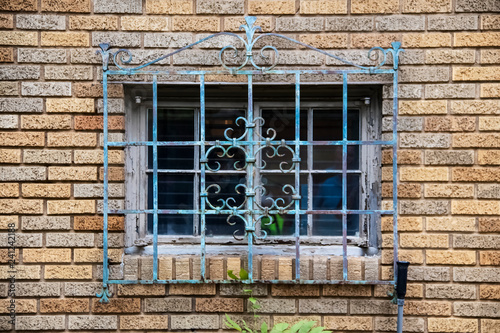 Foto Ornate metal grill with gungy paint over an old window in a brick building - clo