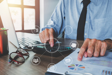 Businessman hand working with financial data and calculator  on desk in modern office.Business analysis and strategy concept with virtual interface icons network diagram.