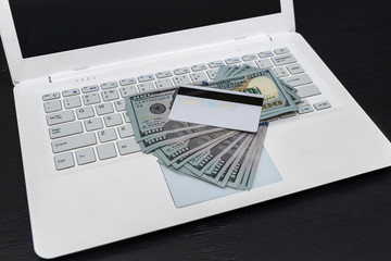 White laptop with dollars and credit card isolated