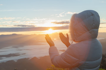 Wall Mural - Christian woman  hands praying to god on the mountain background with morning sunrise. Woman Pray for god blessing to wishing have a better life. Christian life crisis prayer to god.
