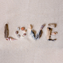Word Love Created Of Seashells And Driftwood In White Sand