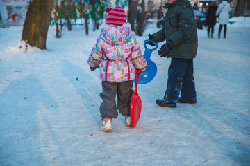 two little kids playing in winter city park with sledges