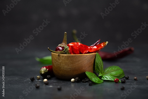 Fotografía chili peppers with basil and peppercorns in bowls on a rustic surface,