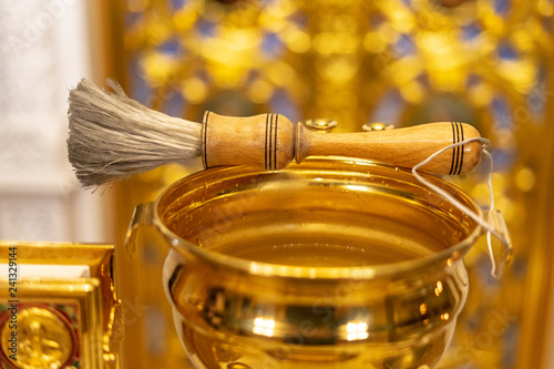 Fotografía Aspergillum lies on the golden bucket with holy water and Gospel