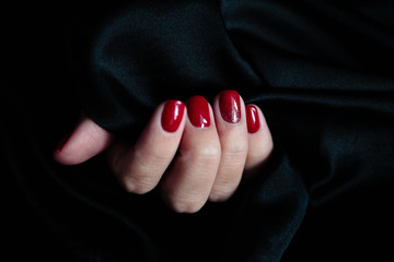 Gorgeous manicure, clssic red color nail polish, closeup photo. Female hands over dark fur background