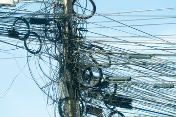 Various types of wires that are messy on the power pole.